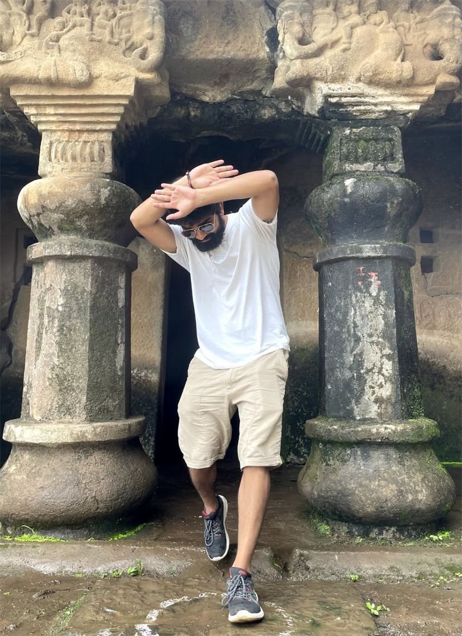 Pratham striking a playful pose between ancient carved temple pillars