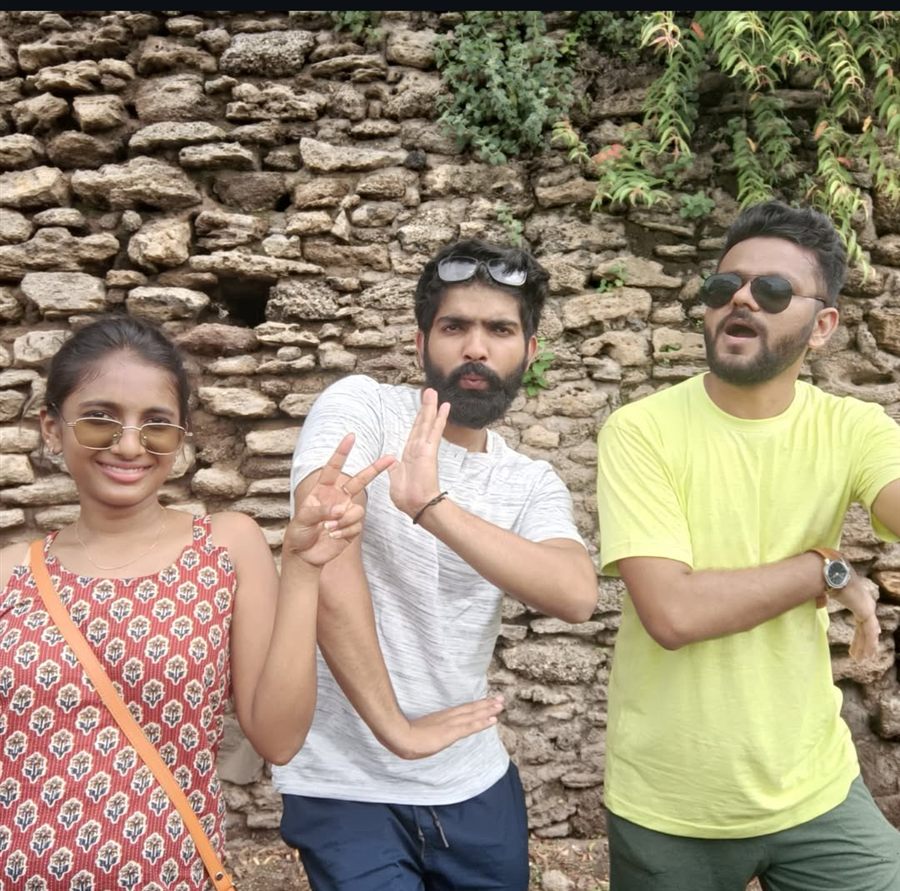 Pratham with two friends, posing playfully against a stone wall